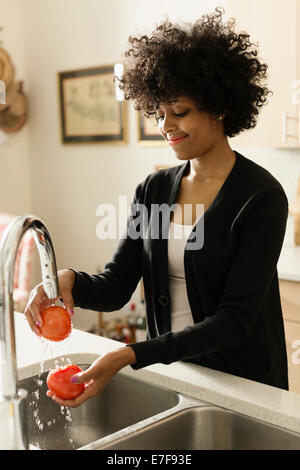 Razza mista donna lavare i pomodori in cucina Foto Stock