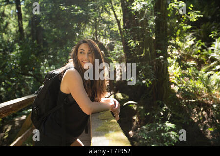 Caucasian donna in piedi sul ponte di legno nella foresta Foto Stock