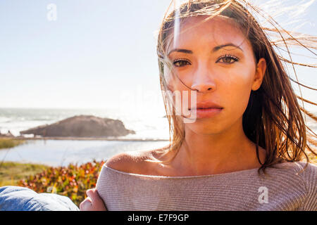 Razza mista donna capelli soffiando nel vento sulla collina costiera Foto Stock