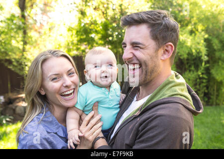 Caucasian giovane azienda baby in cortile Foto Stock