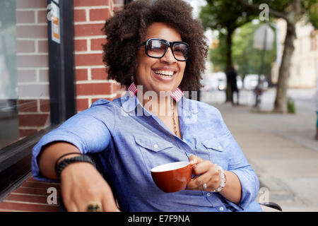 Donna con caffè sulla strada di città Foto Stock