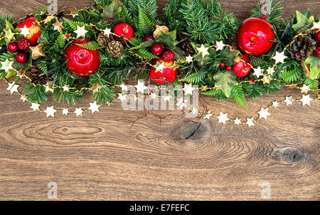 Le decorazioni di Natale ghirlanda con mela rossa e verde di pini rami su sfondo di legno Foto Stock