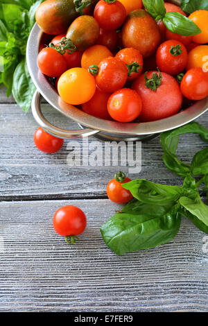 Pomodori ciliegini e basilico vista superiore, nel ferro da stiro scolapasta Foto Stock