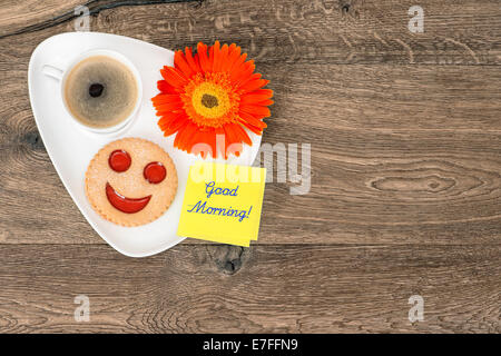 Il caffè con il cookie sorridente e daisy fiore. divertente prima colazione. Campione testo Buongiorno! Foto Stock