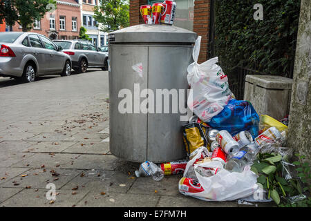 Trabocca spazzatura / pattumiera con cestino intorno e lattine di birra impilati sul top in strada di città Foto Stock