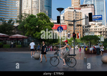 Le donne con una bicicletta in Nanjing Road, Shanghai. Nanjing Road (cinese: 南京路; pinyin: Nánjīng Lù) è la principale strada dello shopping di S Foto Stock