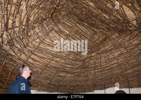 Visitatori turistici dal tetto di paglia nel soffitto ricreato il neolitico Età della pietra hut / stoneage capanne. Esposizione; Visitor Center Stonehenge / Stone Henge REGNO UNITO Foto Stock