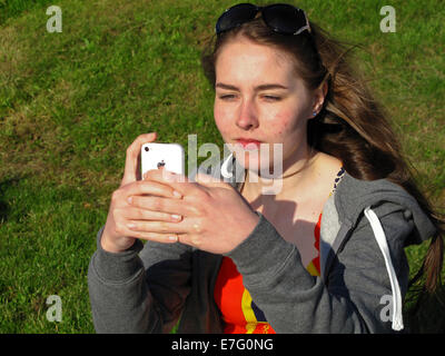 Ragazza adolescente utilizzando iPhone fuori nel sole Foto Stock