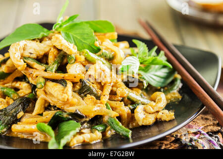 Pollo saltati in padella con cipolla, aglio, pasta di curry, long bean, germogli di bambù e latte di cocco, servita con basilico tailandese Foto Stock