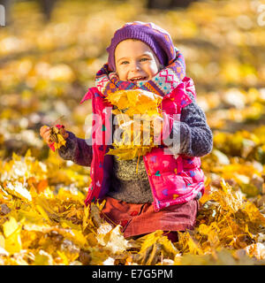 Bambina gioca con foglie di autunno Foto Stock