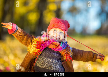 Felice bambina giocare nel parco di autunno Foto Stock