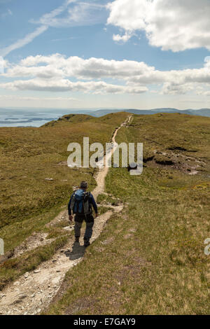 Visualizzazione verticale di un alpinista solitario a piedi giù per un sentiero sul fianco di una collina Foto Stock