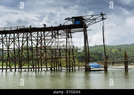 Sangkhla Buri, Kanchanaburi, Thailandia. 16 Sett 2014. Lavoratori sul ponte del ponte di mon. Il 2800 piedi lungo (850 metri) Saphan Mon (Mon ponte) abbraccia la canzone Kalia fiume. Si è riferito il secondo più lungo ponte di legno nel mondo. Il ponte fu gravemente danneggiato durante la pioggia pesante nel luglio 2013 quando il suo piede 230 sezione centrale (70 metri) è collassato durante le inondazioni. © ZUMA Press, Inc./Alamy Live News Foto Stock