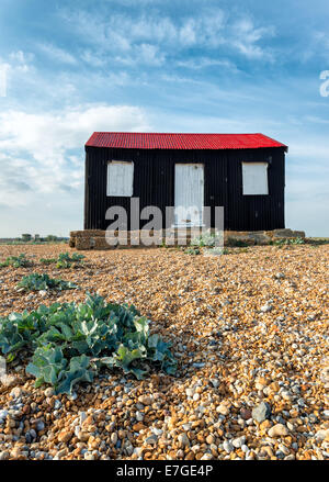 Una capanna nera con un rosso tetto dello stagno su una spiaggia di ciottoli a Rye in East Sussex Foto Stock