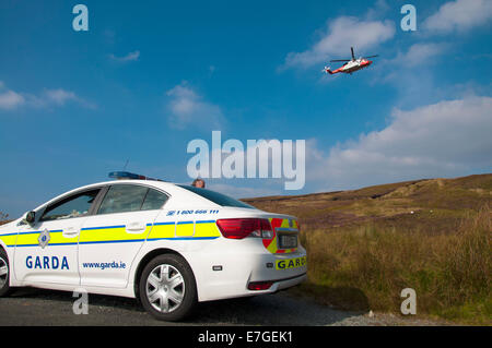 Irish Coast Guard IRCG Garda Cósta na hÉireann Sikorsky elicottero vola sopra un irlandese auto della polizia durante un soccorso medico Foto Stock