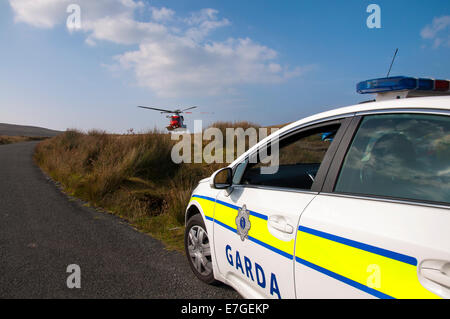 Irish Coast Guard IRCG Garda Cósta na hÉireann Sikorsky elicottero vola sopra un irlandese auto della polizia durante un soccorso medico Foto Stock