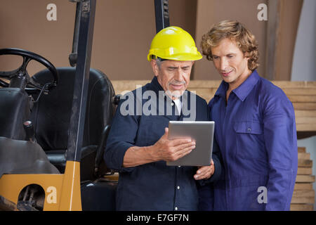 Lavoratori con tavoletta digitale in officina Foto Stock