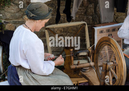 Dimostrazione di filatura della lana da una signora in tradizionale costume bretone Foto Stock