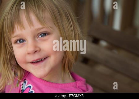 Giovane ragazza sul portico swing guardando la telecamera. Sorridente / felice espressione. Foto Stock