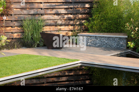 Giardino - Elemental - riflessivo scuro stagno di piscina con bruciato carbonizzato redwood bordo parete ciottoli di basalto in gabbia Foto Stock