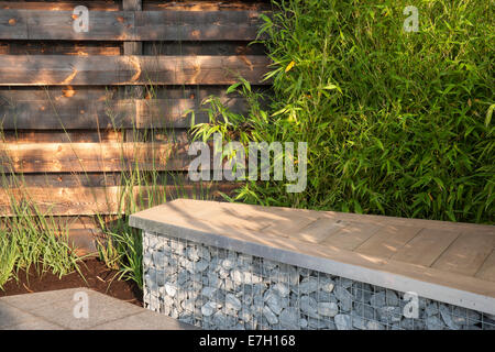 Giardino - Elemental - pietra di basalto patio e ciottoli di basalto in gabbia con redwood posti a sedere in legno piantagione di bamb Foto Stock