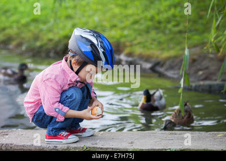 Adorable little boy, alimentando le anatre sul lago Foto Stock