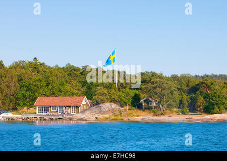 Stoccolma, Svezia - Casa sull isola nell arcipelago con bandiera svedese sul palo. Foto Stock
