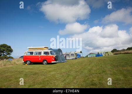 Un rosso VW camper van in un campeggio con decine e cielo blu Foto Stock
