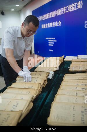 Pechino, Cina. Xviii Sep, 2014. Un membro del personale luoghi archivi originali di operai cinesi costretti in Giappone su una tabella durante un seminario sul rilascio degli archivi compilazione presso il Museo della Guerra del popolo cinese la resistenza contro l'Aggressione giapponese, a Pechino, Cina, Sett. 18, 2014. Dal 1943 al 1945, circa 40.000 cinesi sono stati catturati e portati da parte degli invasori in Giappone, costringendoli a lavorare nelle miniere e siti di costruzione. Un totale di 11.183 morti a causa di sfruttamento spietato, secondo i dati provenienti dal Giappone. © Luo Xiaoguang/Xinhua/Alamy Live News Foto Stock