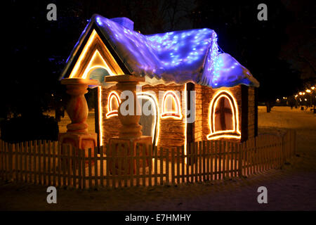 Una piccola casa illuminata di notte in inverno Foto Stock