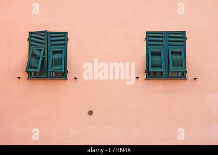 Due verdi finestre in legno sulla facciata rosa Foto Stock