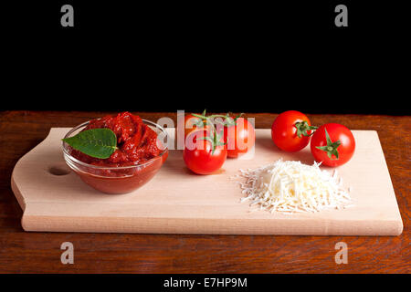 Il concentrato di pomodoro, formaggio grattugiato e alcuni pomodori su legno Foto Stock