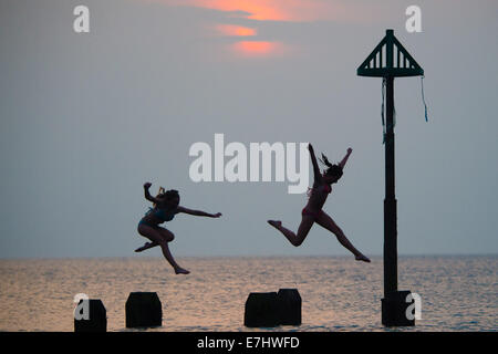 Aberystwyth, Wales, Regno Unito. 18 Settembre, 2014. Come il sole tramonta oltre la calma piatta acque di Cardigan Bay, due ragazze godere il caldo settembre estate indiana, immersioni subacquee e salta fuori il pontile a Aberystwyth sulla West Wales coast. L'incantesimo di liquidare ed insolitamente caldo è previsto per estendersi nel corso del prossimo weekend, ma con il rischio di thundery condizioni e alcune heavy rain Photo credit: Keith Morris/Alamy Live News Foto Stock