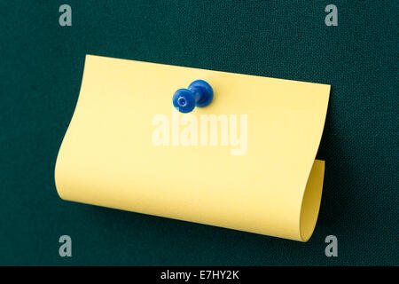 Giallo post-it con blue spingere il pin sulla scheda verde Foto Stock