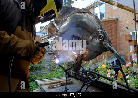 Scultore stick la saldatura di un pesce in metallo Foto Stock