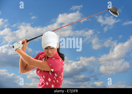 Giocatore di golf femminile swinging golf conducente durante la giornata di sole Foto Stock