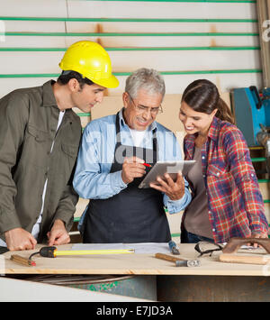 Carpenter utilizzando computer tablet con i colleghi Foto Stock