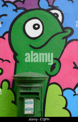 Un verde Irish postbox incorporato in un murale sulla parete a Cork in Irlanda. Foto Stock