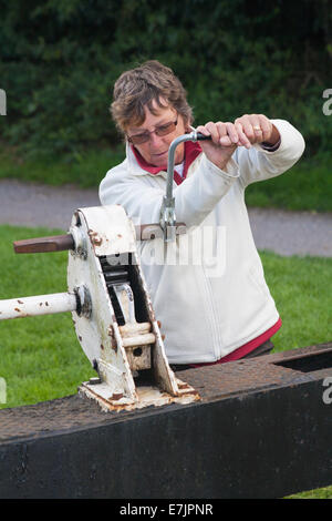 Donna che gestisce cancelli di blocco a Caen Hill Locks, Kennet e Avon Canal, Devizes, Wiltshire, Inghilterra, Regno Unito nel mese di agosto Foto Stock