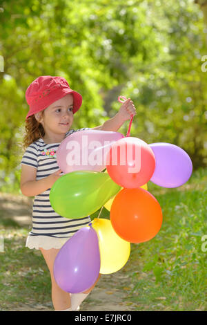 Bambina gioca in estate parco con colorate baloons Foto Stock