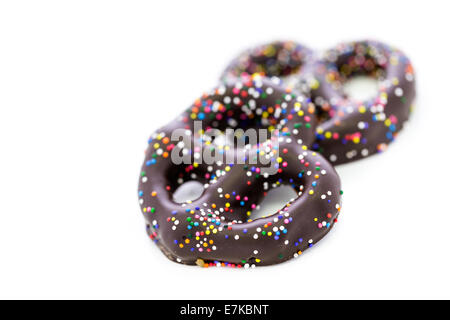 Cioccolato Gourmet pretzel ricoperto di cioccolato coperto pretzel con variopinte spruzza su uno sfondo bianco. Foto Stock