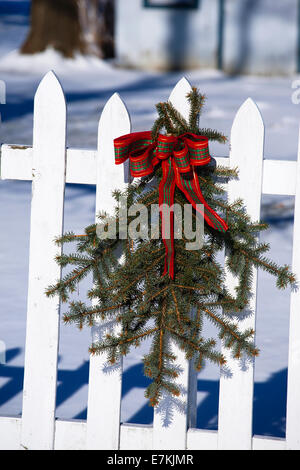 Natale decorazione esterna di pino e di nastro rosso su bianco Picket Fence Foto Stock