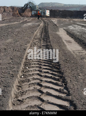 Un enorme mining carrello pneumatico indentation corre verso una massiccia Liebherr pala elettrica in attesa in distanza. Foto Stock