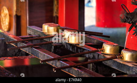 Una fila di cerimoniale di tazze di acqua al santuario di Hakone in Giappone. Foto Stock