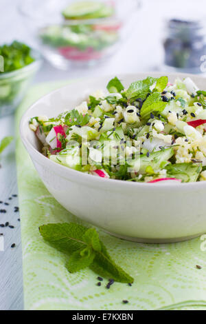 Ciotola piena di couscous fresco con insalata di cetrioli e ravanelli Foto Stock