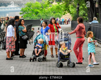 Americano asiatico bambinaie parlare con una madre nel lungomare di Brooklyn, New York. Nota i passeggini e neonati. Foto Stock