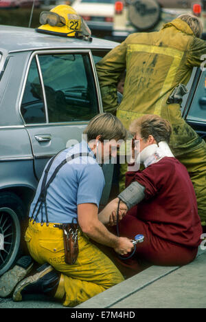 Un paramedico controlla la pressione del sangue di un frastornato auto vittima di incidente in Laguna Hills, CA. Nota collare cervicale. Foto Stock