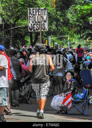 Un evangelista che trasportano un "convertitevi" segno diventa un aspetto aspro come egli mescola con la folla a Puerto Rican Day parade di New York City di Quinta Avenue. Nota Puerto Rican bandiera nella donna la mano. Foto Stock