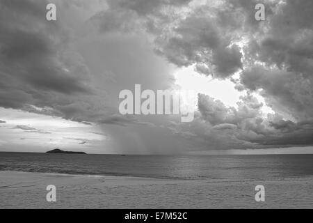 Drammatico cielo tempestoso oltre oceano su una solitaria spiaggia fatto in bianco e nero Foto Stock