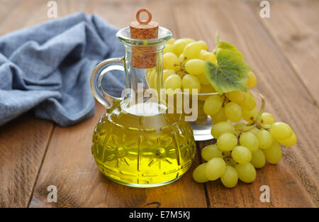 Olio di semi di uva in un vasetto di vetro su sfondo di legno Foto Stock